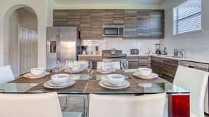 A modern kitchen with a dining area, featuring a stainless steel refrigerator, microwave, and stove. - 172 Balmoral (Haines City)