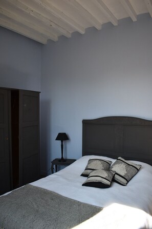 A bedroom with a bed, a nightstand, a lamp, and a wardrobe.