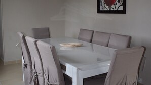 A dining area with a round table and six chairs, each covered with a beige cloth.