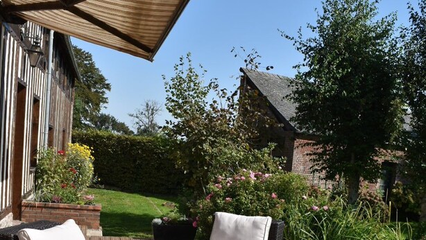 An outdoor deck with wicker furniture, including two sofas and a small table, under a wooden pergola.
