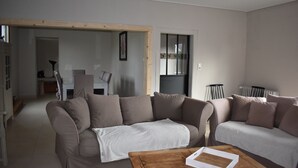 A living room with two sofas, a coffee table, and a dining area in the background.