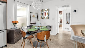 A modern kitchen with a dining area, featuring a round table, chairs, and a refrigerator. - 1 BR - Guesthouse - A beachside gem! Walk 1 min to Beach! (Boca Raton)
