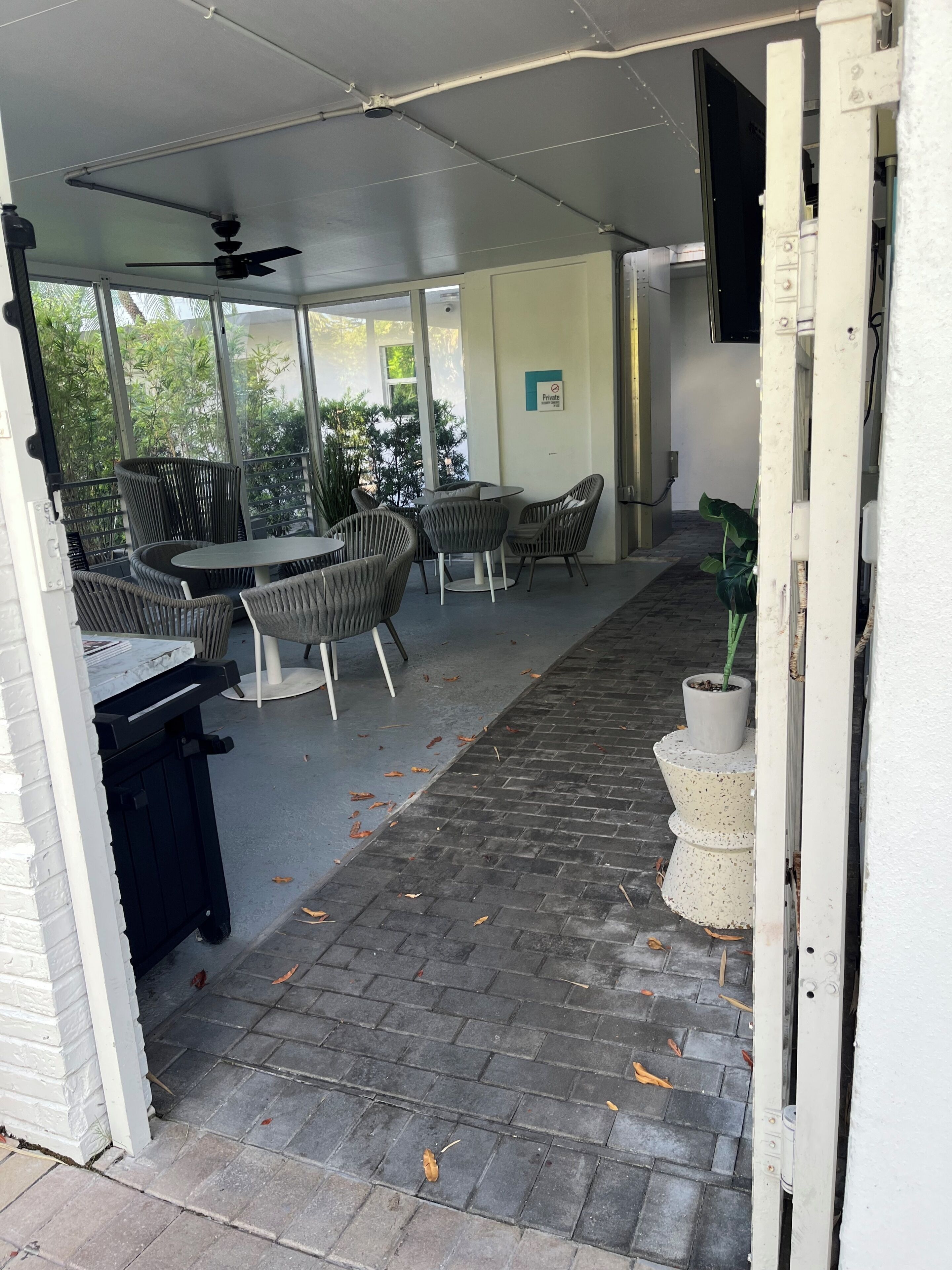 An outdoor patio area with a covered seating area, a table, and chairs.