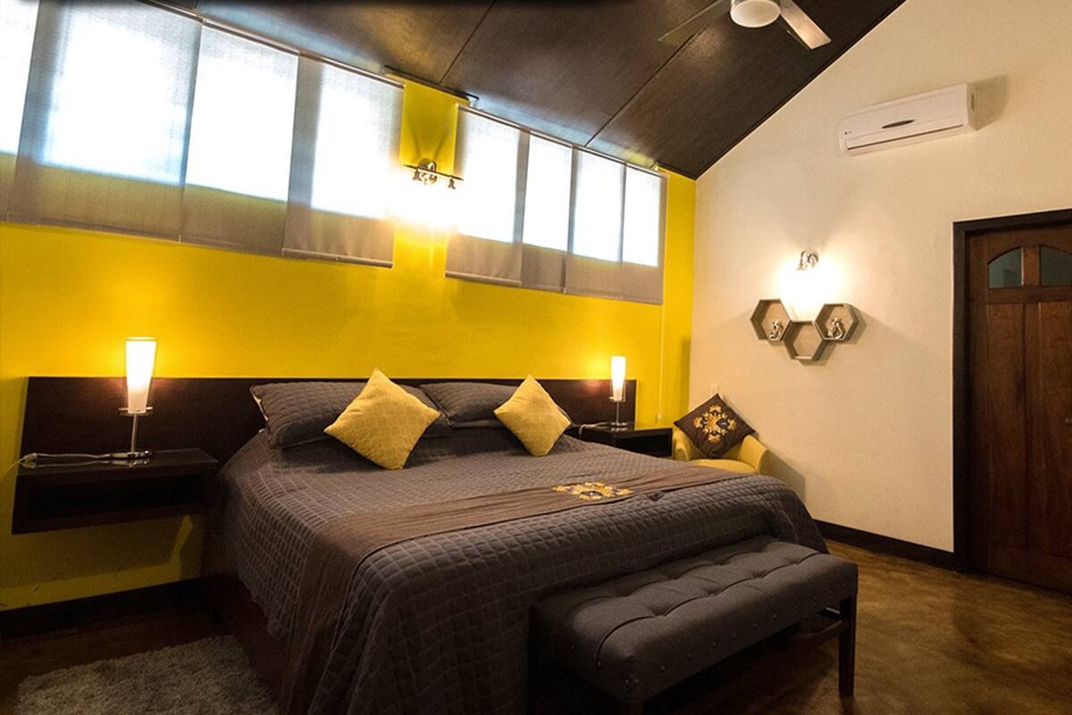 A bedroom with a bed, bedside tables, a bench, a window, and a door.
