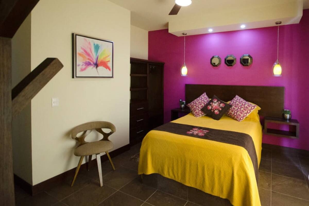 A bedroom with a bed, a chair, a dresser, and a ceiling fan.