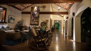 A spacious living area with a high ceiling, wooden beams, and a dining table with chairs.