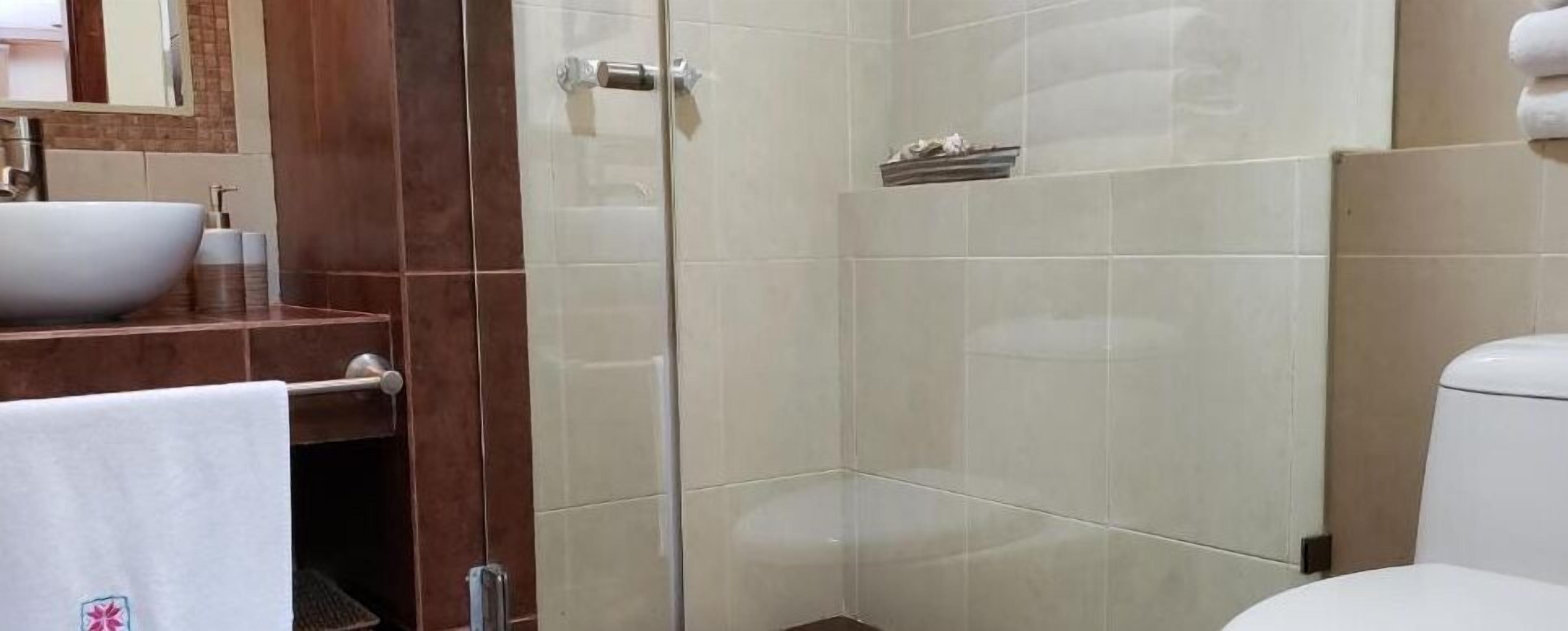 Un bany amb un lavabo blanc, un armari de dutxa de vidre i un vàter.