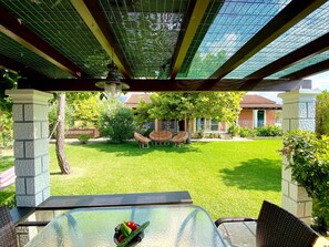 A covered patio with a glass table, chairs, and a small fire feature.