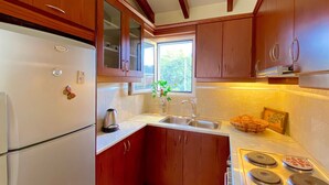 Une cuisine avec des meubles de rangement en bois, un réfrigérateur blanc, un évier et une cuisinière.