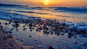 Une plage de galets, avec des vagues au coucher du soleil.