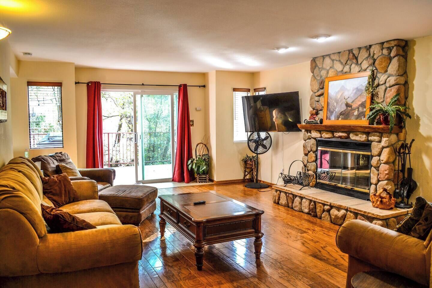 A living room with a stone fireplace, a television, and a sofa.