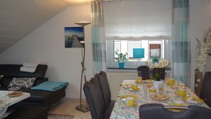 Un comedor con una mesa dispuesta para cuatro, un sofá y un radiador.