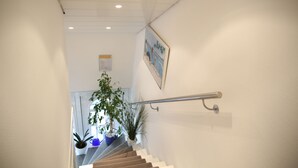 Una escalera con barandilla, plantas en macetas y un cuadro en la pared.