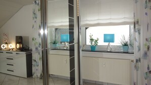 Una cocina moderna con separador de vidrio, muebles blancos y ventana con vistas.