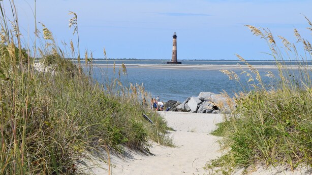A coastal path leading to a lighthouse with a clear view of the sea and distant shoreline. - Walk to restaurants! 10min to beaches and downtown Charleston.  (Mount Pleasant)