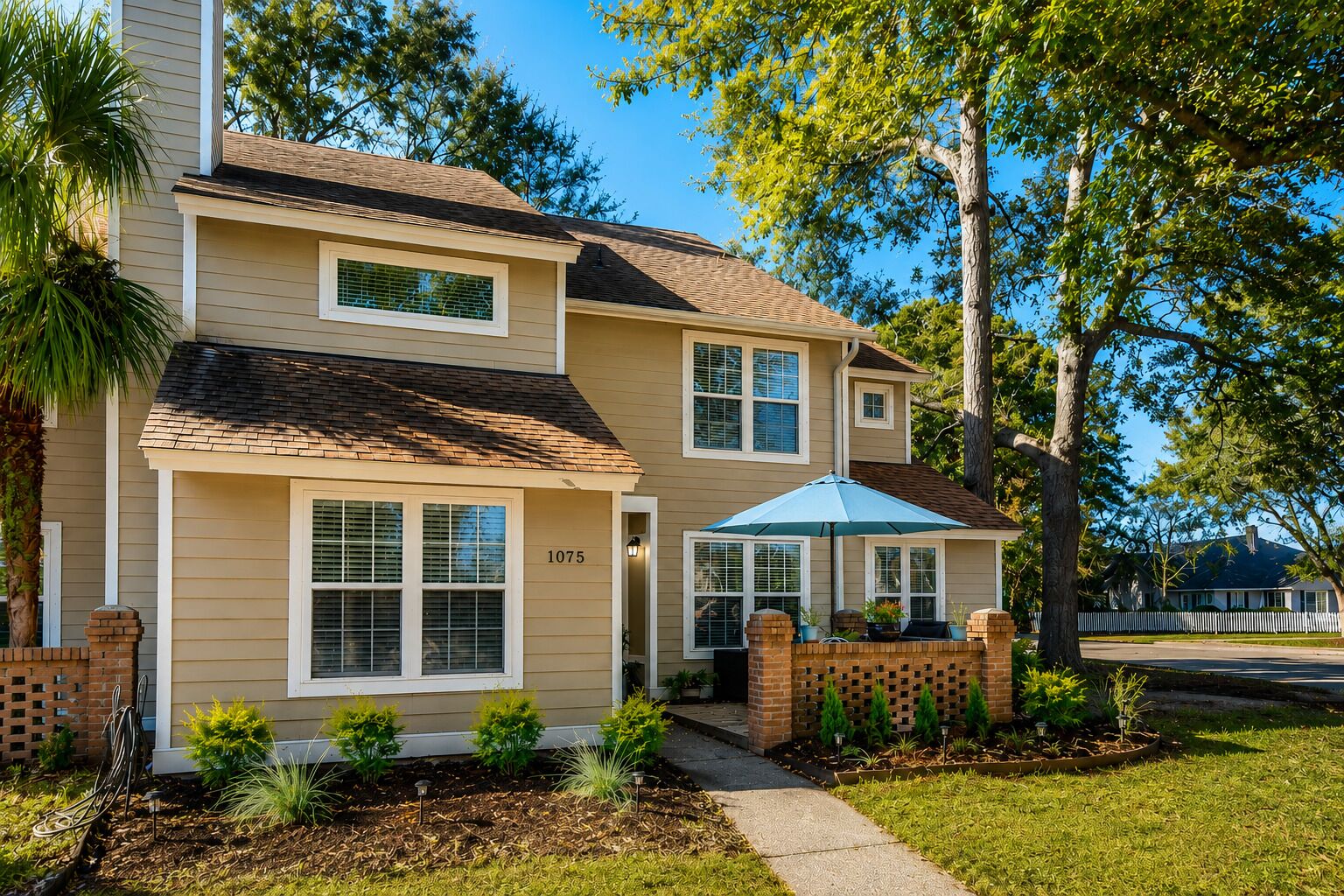 A two-story house with a number '1075' on the front, a brick entryway, and a small front yard with plants and a pathway.