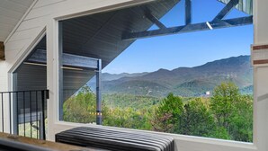Ein Zimmer mit einem großen Fenster und Blick auf eine gebirgige Landschaft.