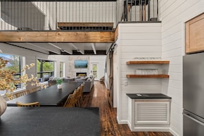 A modern kitchen with a large island, built-in shelves, and a stainless steel refrigerator. - YARD/Hot Tub/Game Room/Theater/VIEWS/Fire Pit - Garrett Lodge (Gatlinburg)