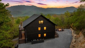 Eine rustikale Holzhütte mit einer Terrasse, umgeben von bewaldeten Hügeln.