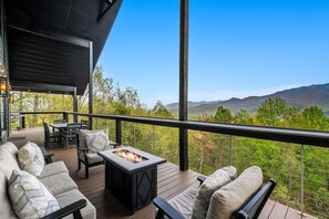 A deck with outdoor furniture, a fire pit, and a scenic mountain view. - YARD/Hot Tub/Game Room/Theater/VIEWS/Fire Pit - Garrett Lodge (Gatlinburg)