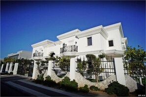 Stately building with a classic design, surrounded by a well-manicured garden and a secure black iron fence.