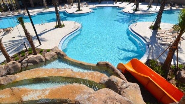 A large outdoor swimming pool with multiple sections, surrounded by palm trees and lounge chairs. - 4627 Solterra (Davenport)