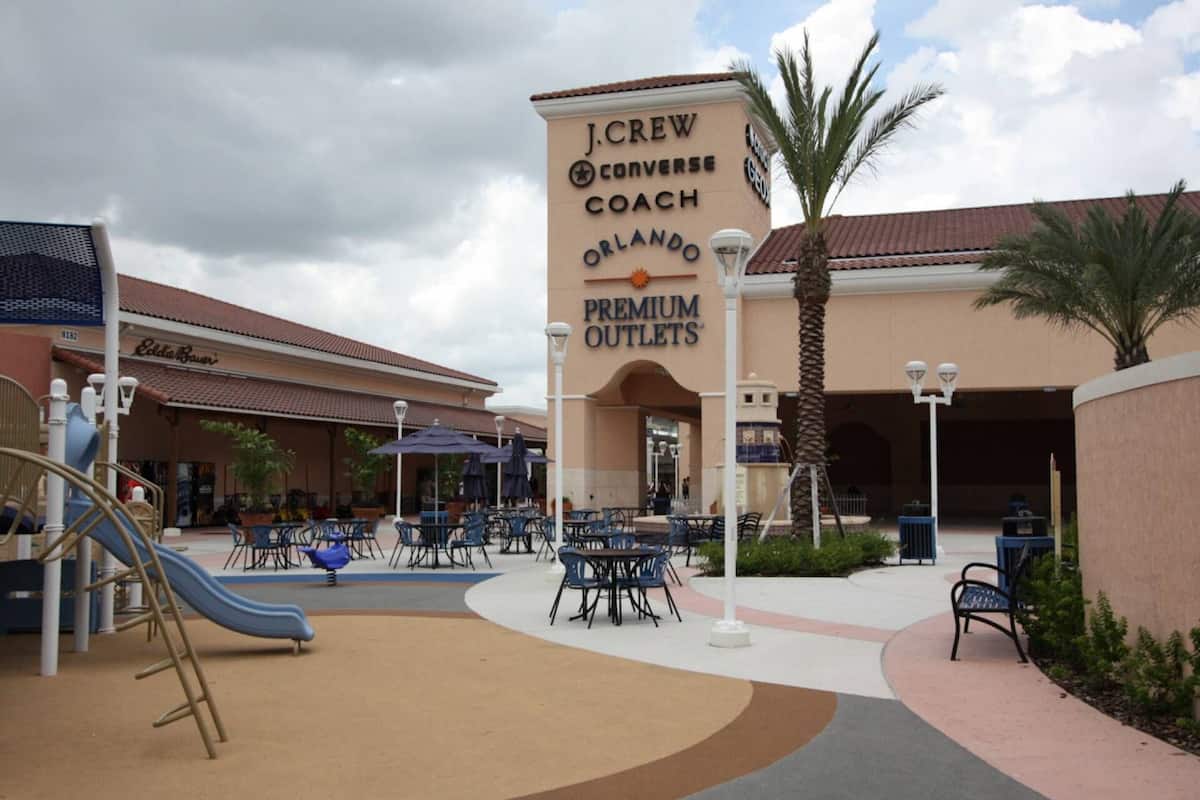 A J.Crew Converse Coach Orlando Premium Outlets store with outdoor seating and a playground area.