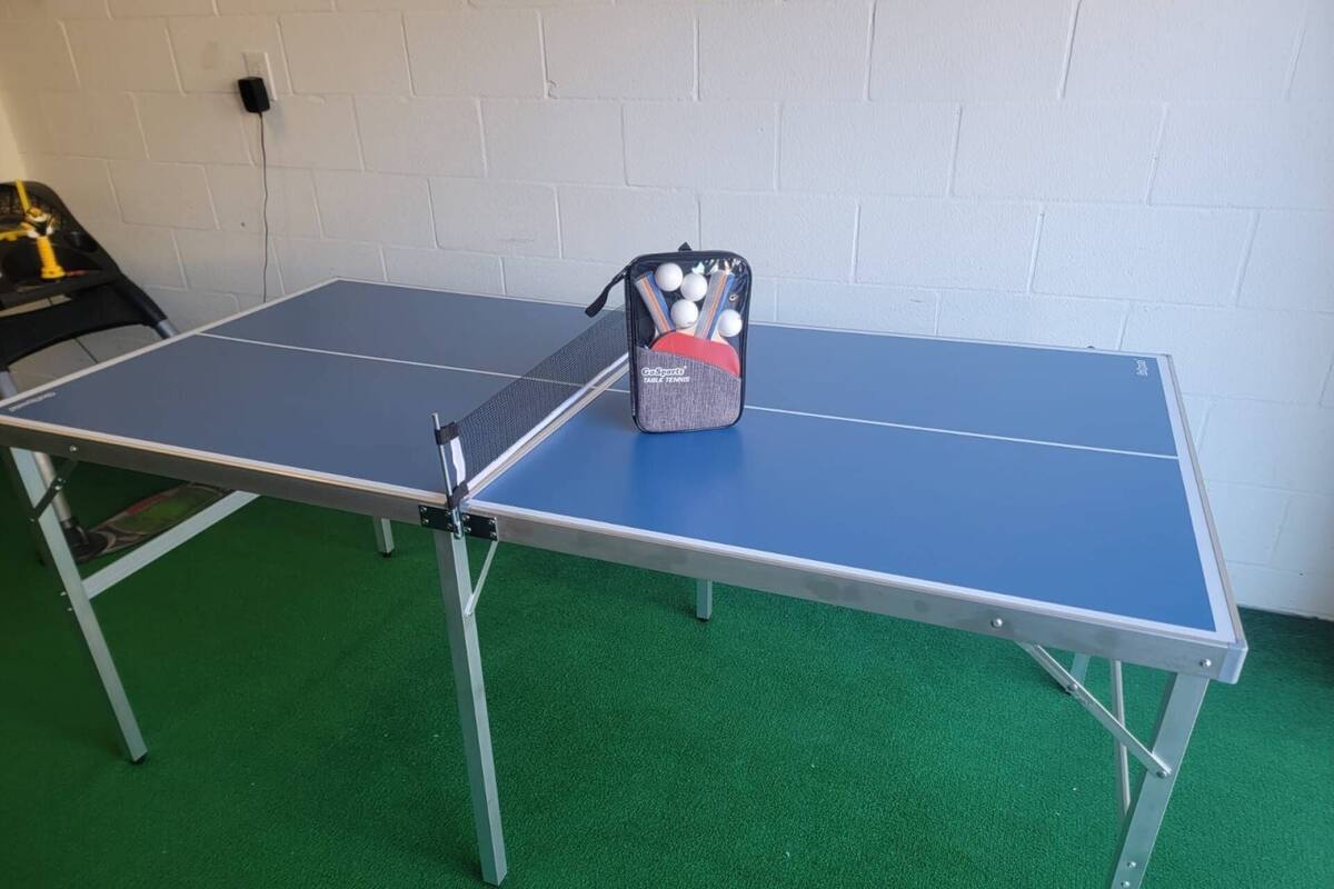 A ping pong table with a bag of balls and paddles on it.