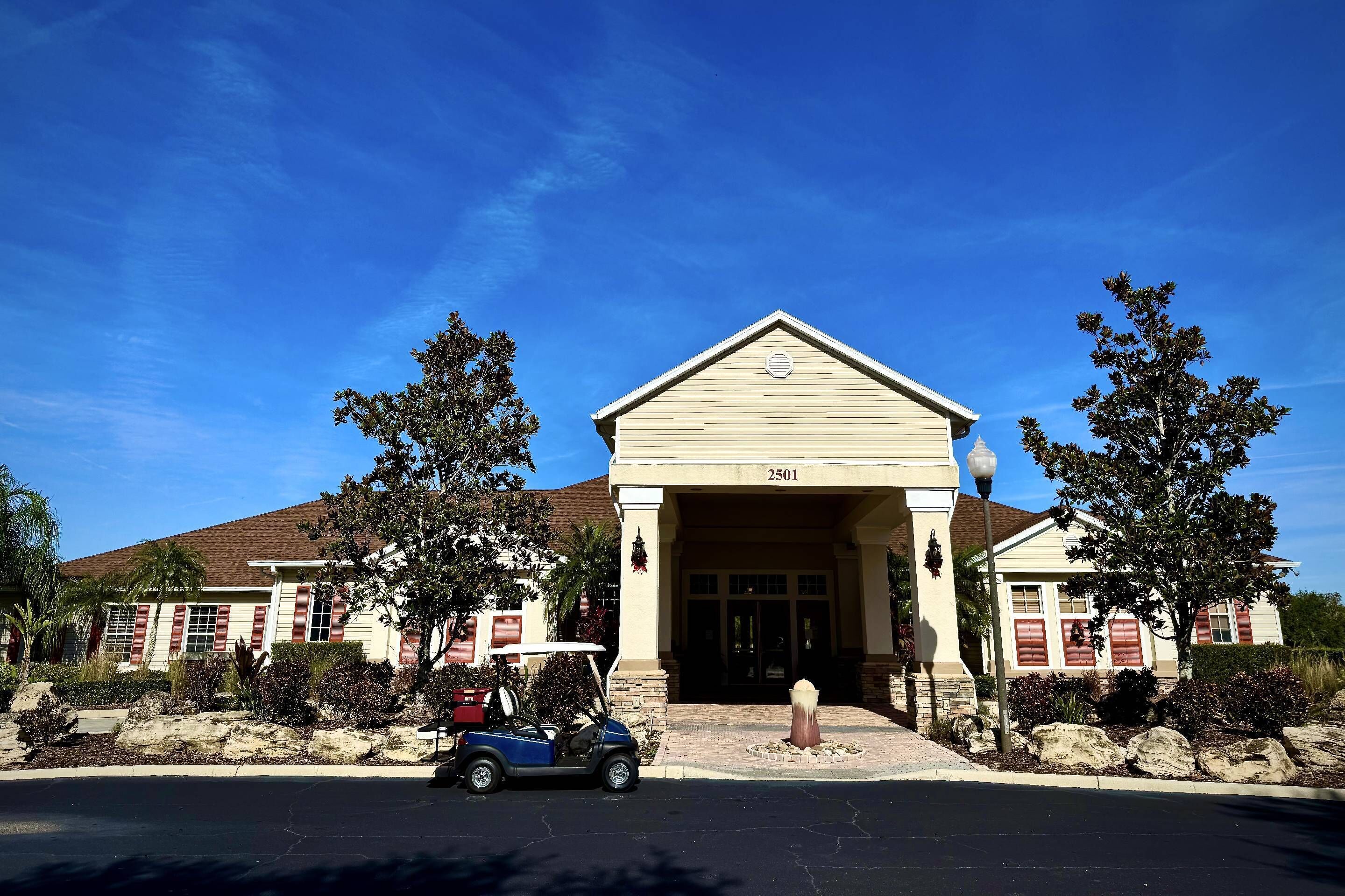 A beige building with a number 2501, a covered entrance, and a golf cart parked in front.