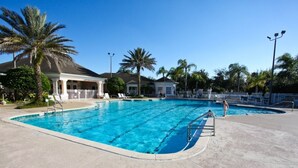 A swimming pool with a clear blue water, surrounded by palm trees and a covered area with lounge chairs. - 8118 Windsor Palms (Kissimmee)