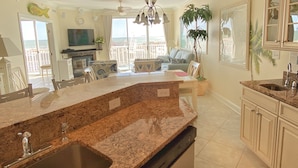 A kitchen with granite countertops, a dishwasher, and a sink. There is a dining area with a table and chairs. A large window provides a view of the ocean. - 🏖️Fabulous Ocean Views in Belmont Towers on Boardwalk. AC, Pool, Gym🏖️ (Ocean City)