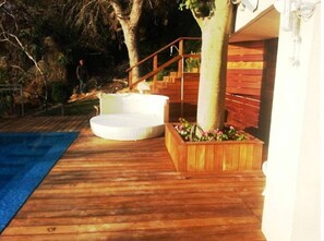 Relax on the deck with a hot tub or lounge chair, surrounded by lush greenery and a beautiful planter box.