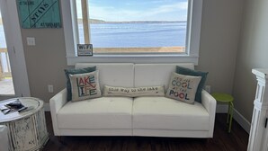 A white sofa with three cushions, a small green stool, and a sign about Wi-Fi availability.