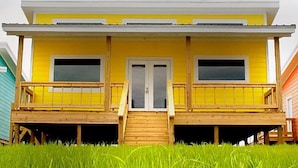 A yellow house with a front porch, two windows, and a door.