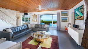A modern living room with a leather sofa, glass coffee table, and a view of the ocean. - Iconic Ted Williams Estate. Bayfront, Heated Infinity Pool & Hot Tub, Dockage. (Islamorada)