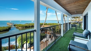 A balcony with a view of the ocean, a wooden ceiling, and outdoor seating. - Iconic Ted Williams Estate. Bayfront, Heated Infinity Pool & Hot Tub, Dockage. (Islamorada)