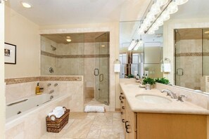 A modern bathroom with a large bathtub, a walk-in shower, and a vanity with a large mirror. - Homes (Aspen)