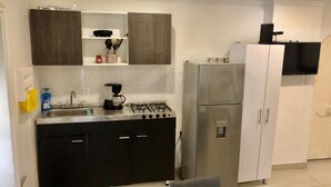 A compact kitchen with a gas stove, a refrigerator, and a microwave. - BEAUTIFUL APARTMENT STUDIO IN HISTORICAL CENTER  (Cartagena)