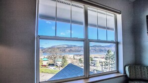 A room with a large window offering a view of a lake and distant hills. - Enjoy the View - 2 Bedrooms, 2 Bathrooms - Upstairs Condo Blocks from Downtown (Hood River)