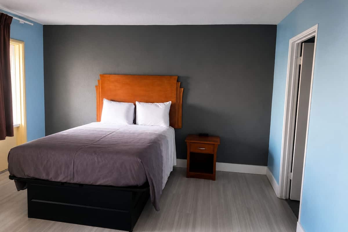 A bedroom with a bed, a nightstand, and a door.