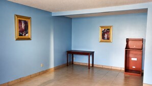 Ein Zimmer mit blauen Wänden, einem Holztisch und zwei gerahmten Bildern.