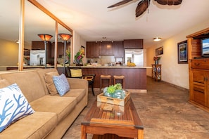 Relax in this open-plan living space featuring a comfortable sofa, kitchen island, and large mirror.