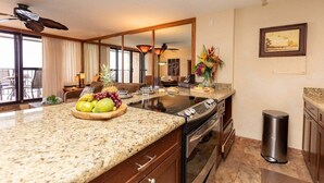 A modern kitchen with granite countertops, a built-in oven, and a dining area with a table and chairs.
