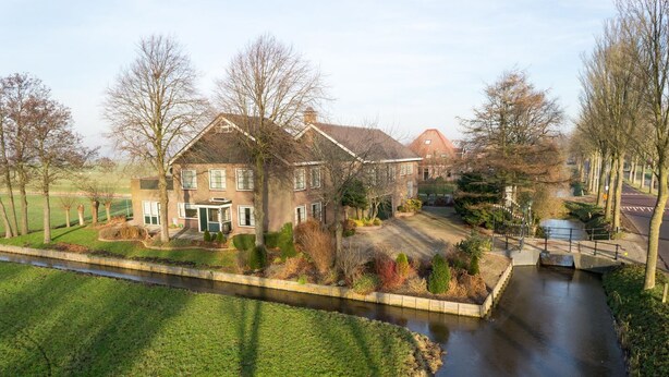 A residential area with a canal, houses, and a well-maintained lawn. - 6-10 pers family home in the country, 15km from Amsterdam (Wijdewormer)