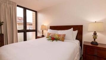 A neatly made bed with white linens, a colorful pillow, and a small decorative item on the nightstand.