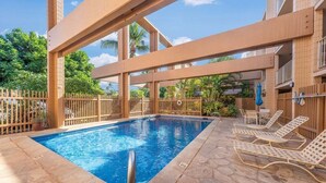 Una piscina con sillones de descanso y una valla de madera.