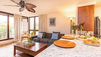 Een moderne woonkamer met een bank, salontafel en een eetgedeelte met een marmeren aanrecht.