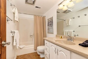 A bathroom with a bathtub, toilet, and sink.