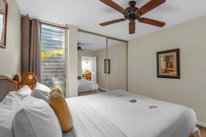 Ein Hotelzimmer mit einem Bett, einem Deckenventilator, einer Tür, die auf einen Balkon führt, und einem gerahmten Bild an der Wand.