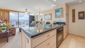 A spacious kitchen with a large island, a dining area with a view of the ocean, and a living room with a balcony.